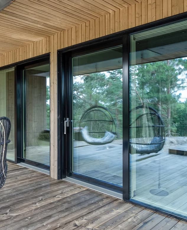 Patio with wooden deck, large glass doors, and two hanging egg chairs.