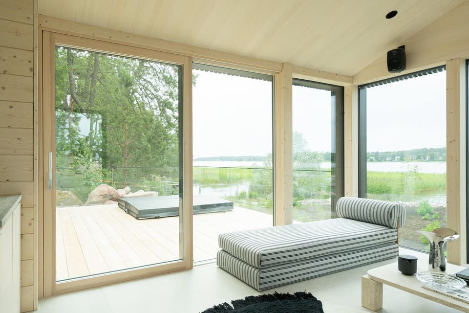 Bright, minimalist lounge area with light wood walls and large glass windows offering a scenic view.