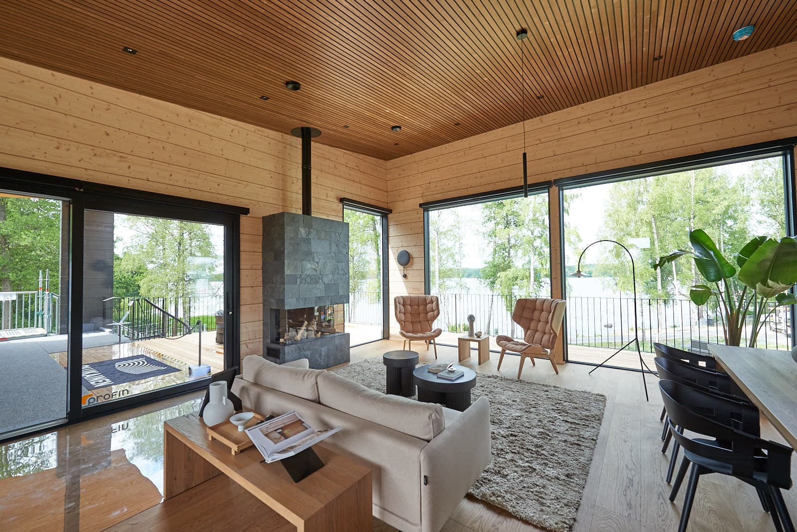 Wood-paneled living room with concrete fireplace and panoramic lake views