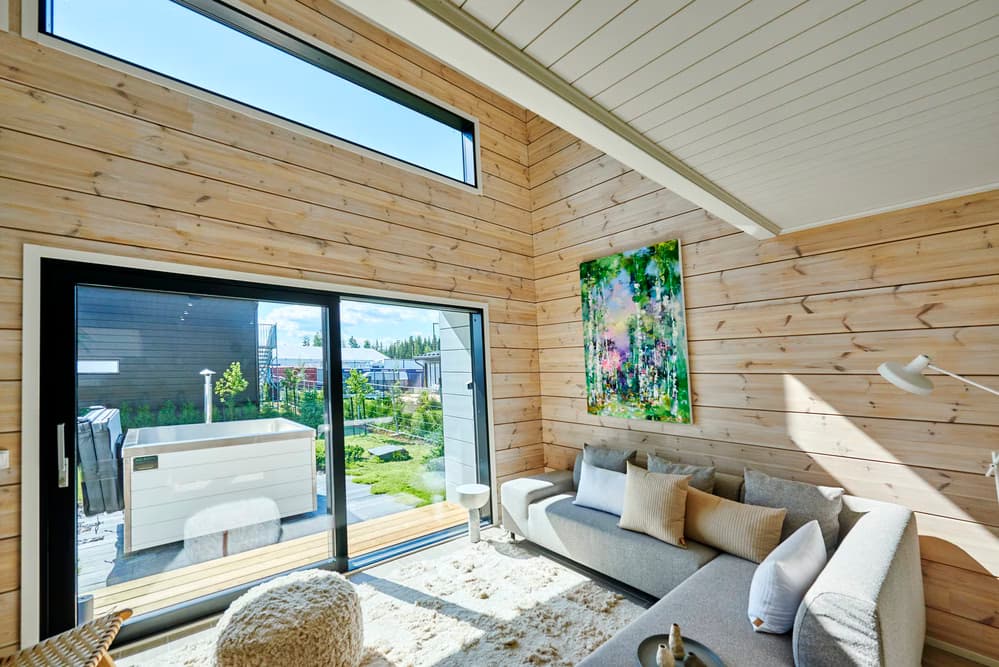 Scandinavian-style living room with wood walls and outdoor hot tub access