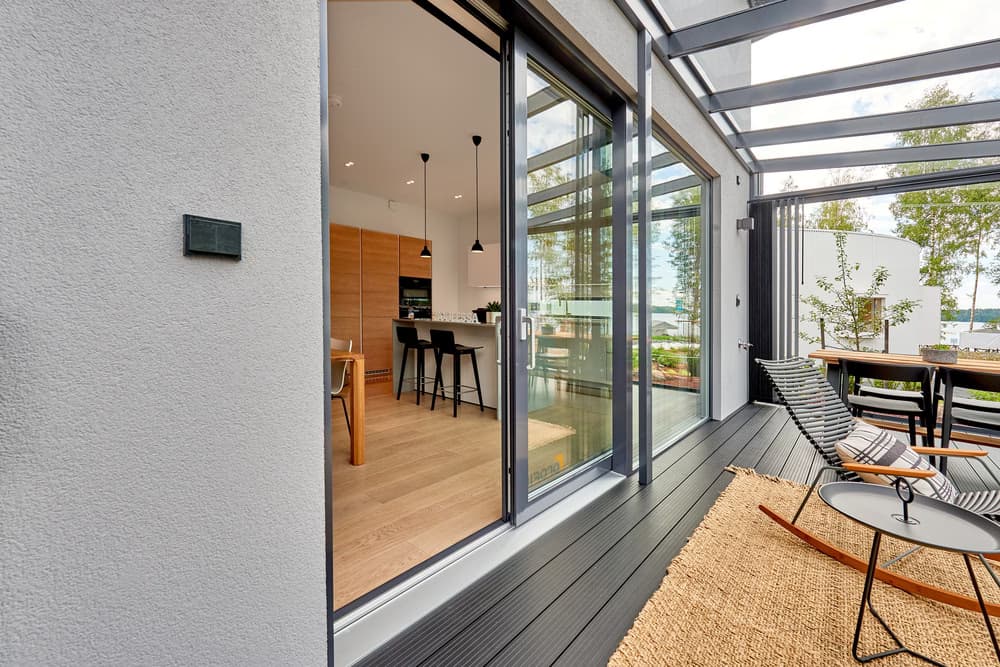 Covered patio with glass doors opening to modern kitchen interior