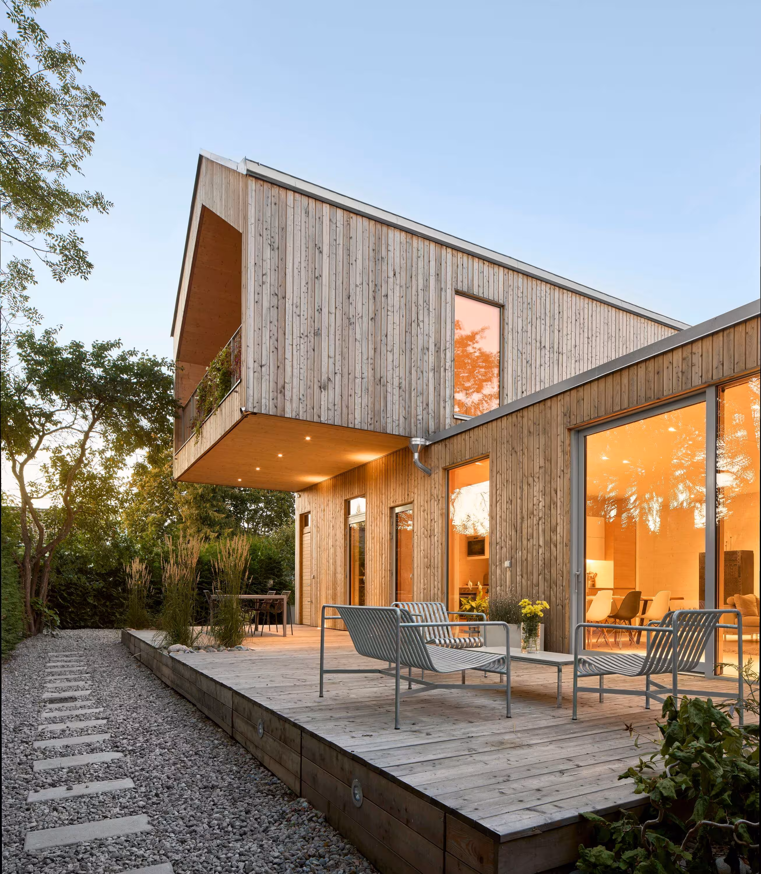 Modern wood-clad house with cantilevered upper floor at dusk