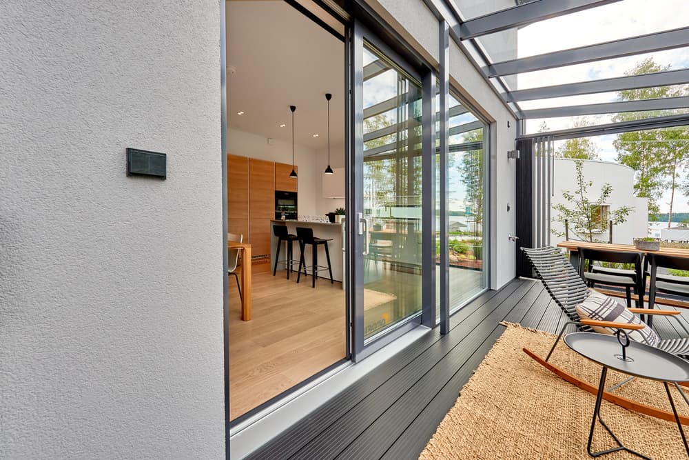 Covered patio with glass doors opening to modern kitchen interior